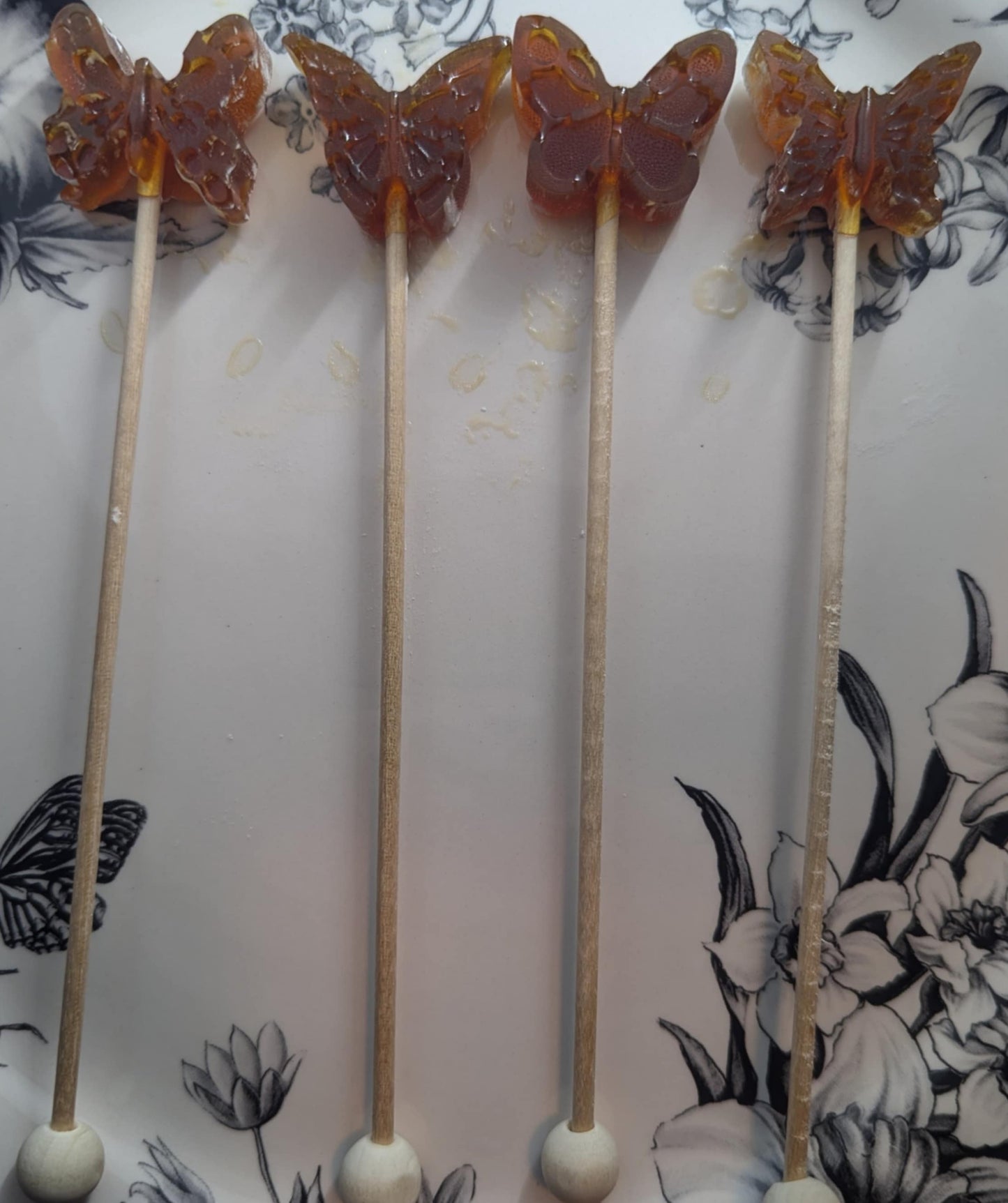 Butterfly-shaped lollipops on sticks with a floral patterned background