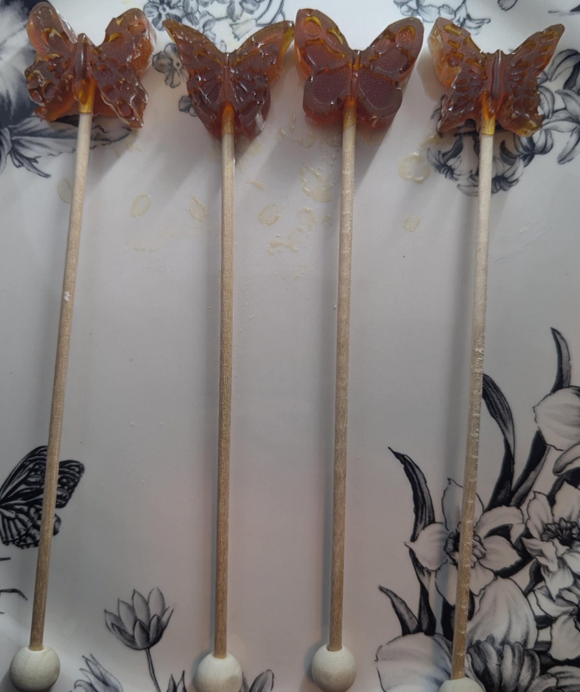 Butterfly-shaped lollipops on sticks with a floral patterned background